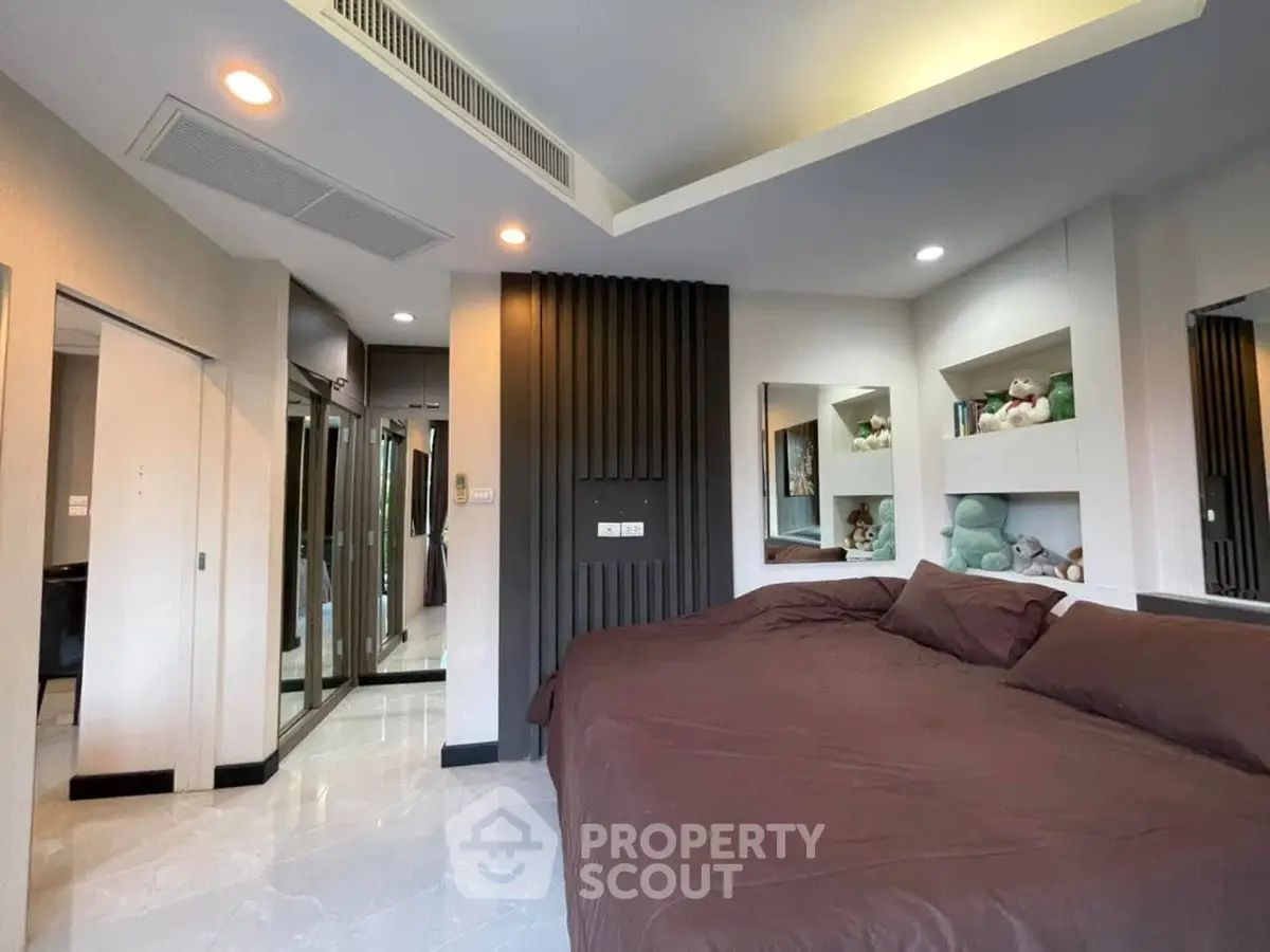 Modern bedroom with stylish decor and built-in shelving, featuring cozy bedding and ambient lighting.