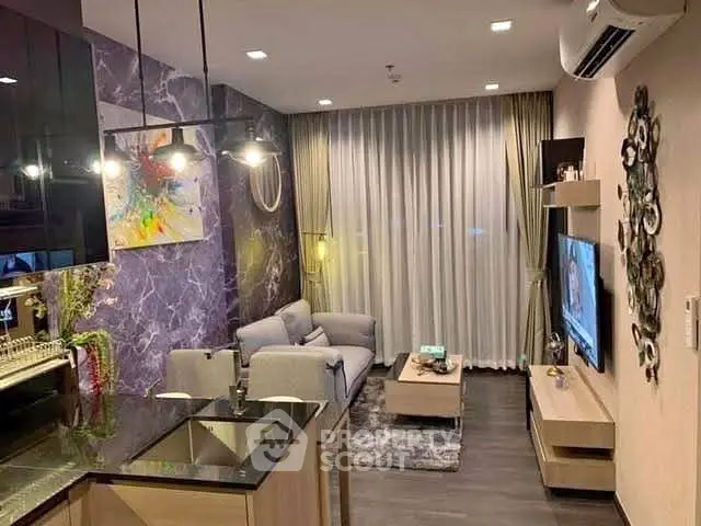 Modern living room with stylish decor and open kitchen layout, featuring cozy seating and contemporary lighting.