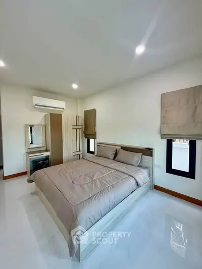 Modern bedroom with sleek design, featuring a comfortable bed, air conditioning, and ample natural light.