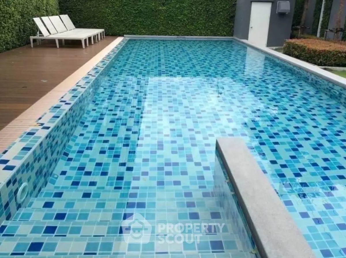 Luxurious outdoor swimming pool with modern tile design and sun loungers, perfect for relaxation.