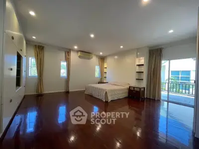 Spacious bedroom with polished wooden floors and balcony access.