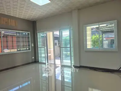 Spacious living room with large windows and glossy tiled floors, offering abundant natural light and modern design.