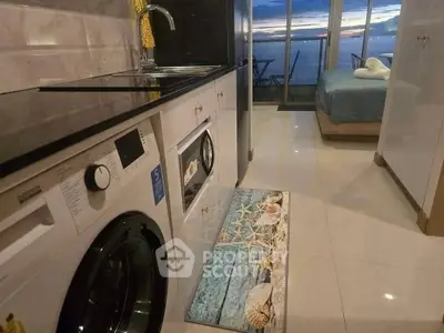 Modern studio apartment with ocean view, featuring sleek kitchen and cozy bedroom.