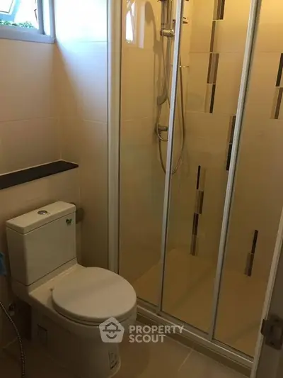 Modern bathroom with shower enclosure and toilet in a compact space.