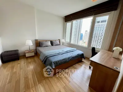 Spacious bedroom with city view, wooden flooring, and modern furniture in a high-rise apartment.