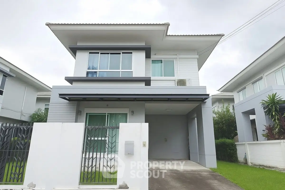Modern two-story house with sleek design and spacious driveway in suburban neighborhood.