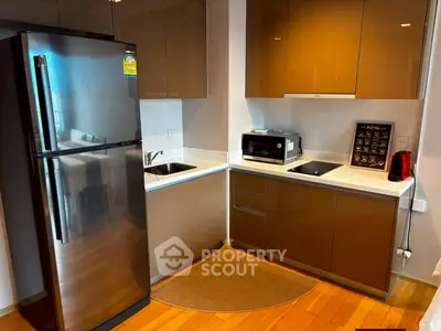 Modern kitchen with sleek cabinets, stainless steel fridge, and compact appliances in a cozy apartment.