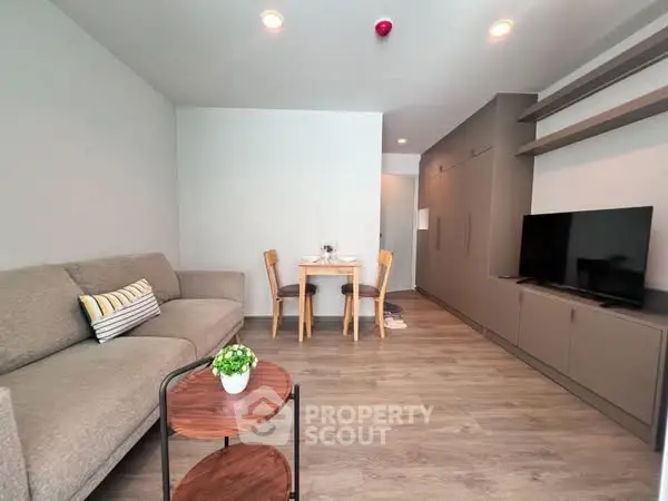 Modern living room with cozy sofa, TV, and dining area in open layout apartment.