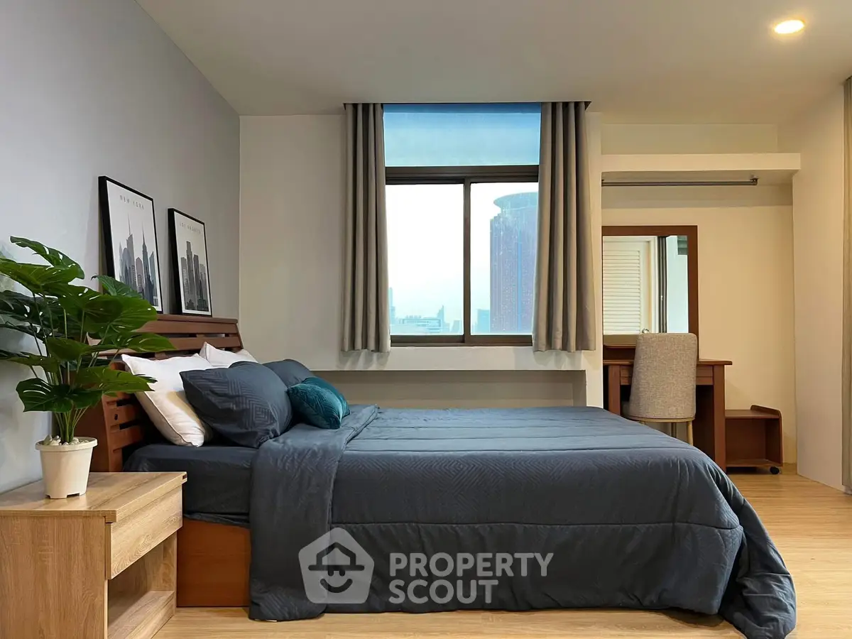 Spacious bedroom with modern decor and city view, featuring a cozy bed and stylish furnishings.