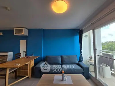 Modern living room with blue accent wall and cozy sofa, featuring a balcony with a view.
