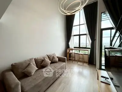Modern living room with high ceiling and large windows offering city views.