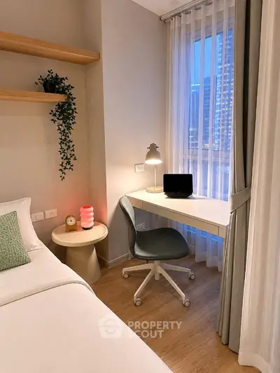 Cozy bedroom with study nook, featuring a desk, chair, and window view in a modern apartment.