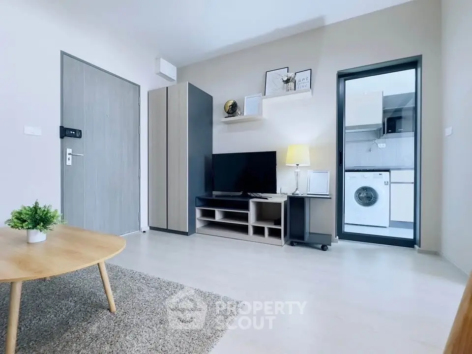 Modern living room with stylish decor and adjacent laundry area in a contemporary apartment.
