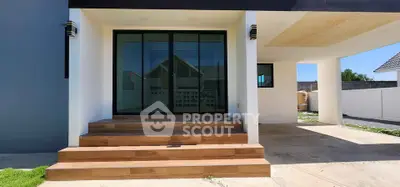Modern house entrance with wooden steps and large glass doors, showcasing sleek architectural design.