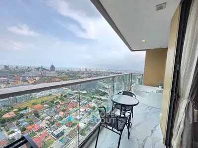 Stunning high-rise balcony with panoramic city view and cozy seating area.
