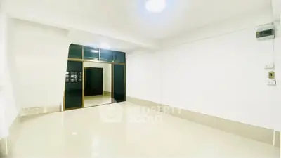 Spacious empty room with glossy tiled floors and large glass doors, ideal for customization.