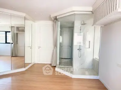 Spacious bedroom with glass-enclosed shower and mirrored closet doors