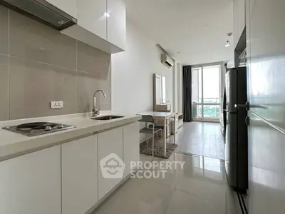 Modern kitchen with sleek white cabinetry and integrated appliances in a bright apartment.