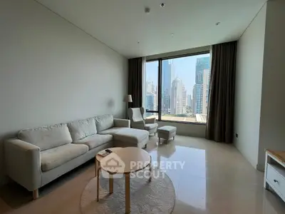 Modern living room with city view, featuring cozy seating and large window.