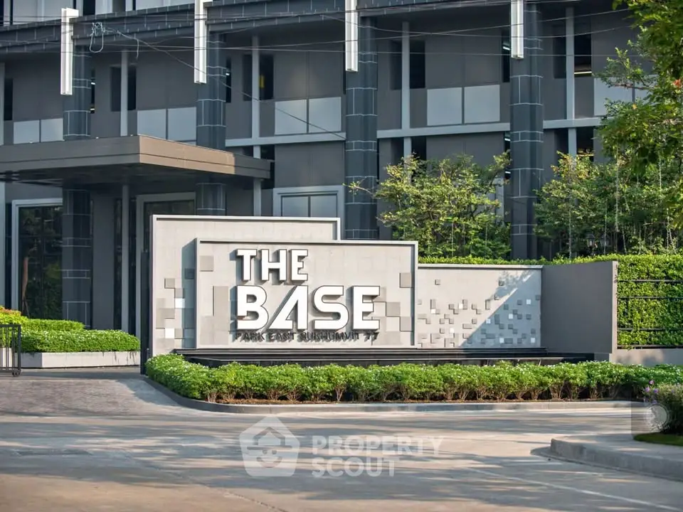 Modern building entrance with stylish signage and lush greenery