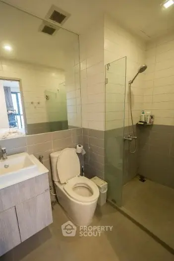 Modern bathroom with glass shower and sleek fixtures in contemporary apartment.