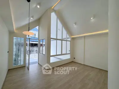 Spacious modern living room with high ceilings and large windows, offering abundant natural light.