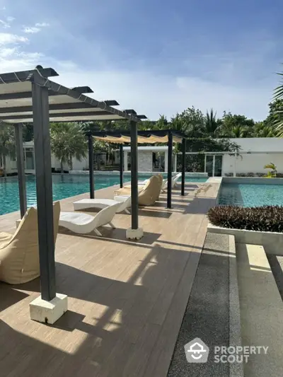 Luxurious outdoor pool area with stylish loungers and pergolas, perfect for relaxation and leisure.