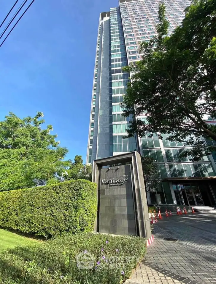 Modern high-rise building with lush greenery and clear blue sky
