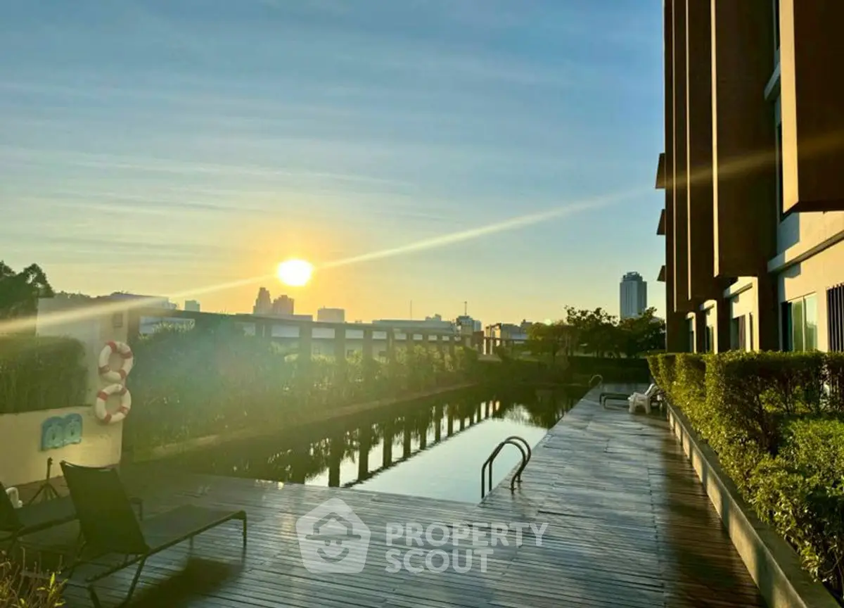 Stunning sunrise view over modern apartment poolside with city skyline backdrop.