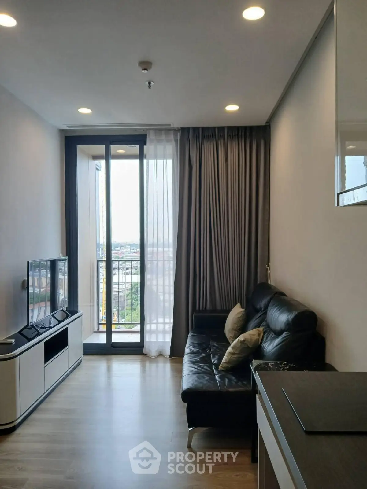 Modern living room with balcony view, sleek furniture, and natural light.