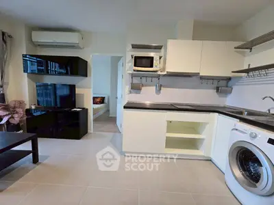 Modern kitchen with washing machine and sleek cabinetry in open layout apartment.
