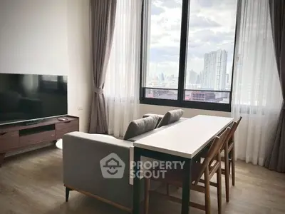 Modern living room with city view, stylish furniture, and large windows.