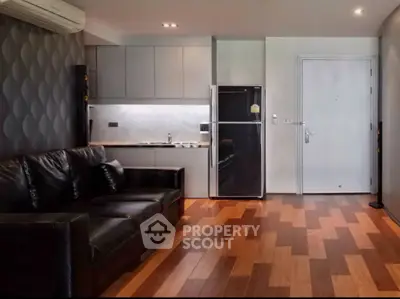 Modern living room with sleek black leather sofa and stylish kitchen area