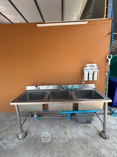 Stainless steel triple sink with water filtration system in outdoor setting