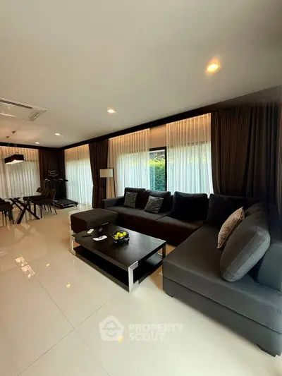 Luxurious modern living room with elegant dark furnishings and large windows.