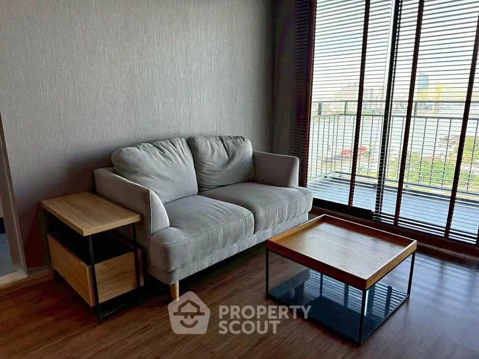 Cozy living room with modern sofa and wooden coffee table near large window with city view.