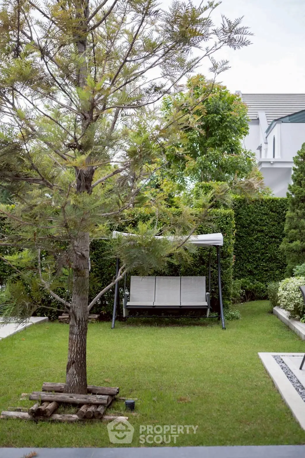 Charming garden with lush greenery and cozy swing, perfect for relaxation and outdoor enjoyment.