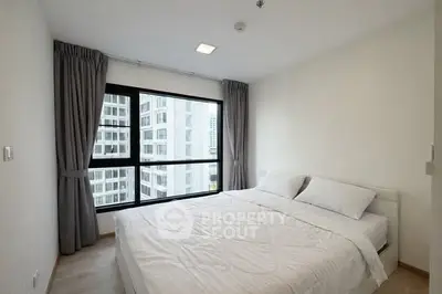 Modern bedroom with large window and city view in high-rise apartment