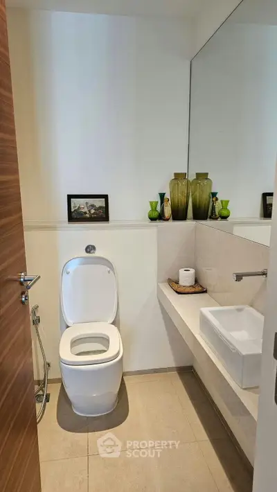 Modern bathroom with sleek fixtures and elegant decor, featuring a wall-mounted sink and stylish accessories.