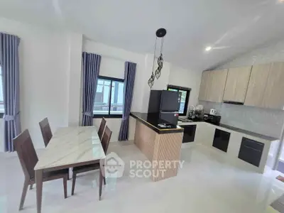 Modern kitchen with sleek cabinetry and dining area in a bright, open layout