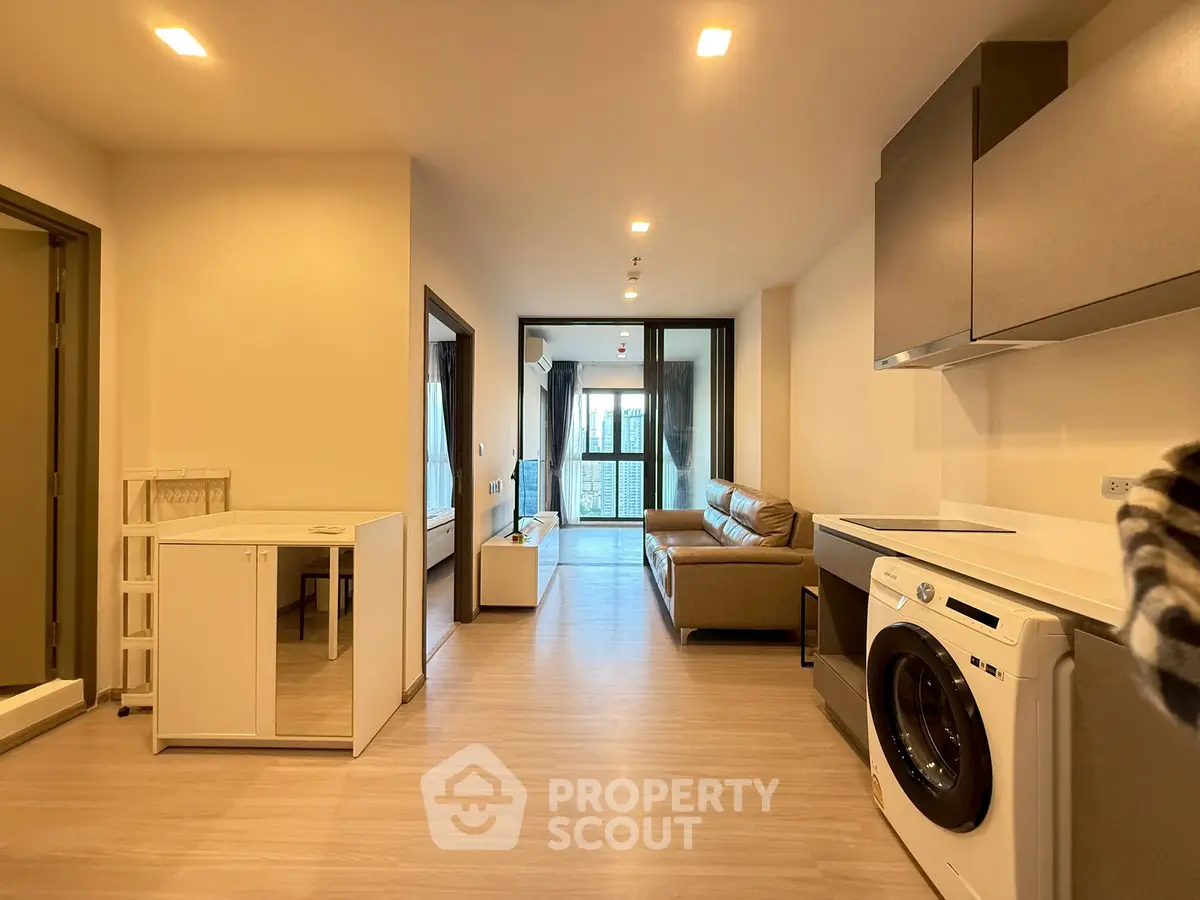 Modern apartment interior with open layout, featuring a cozy living area and in-unit washing machine.