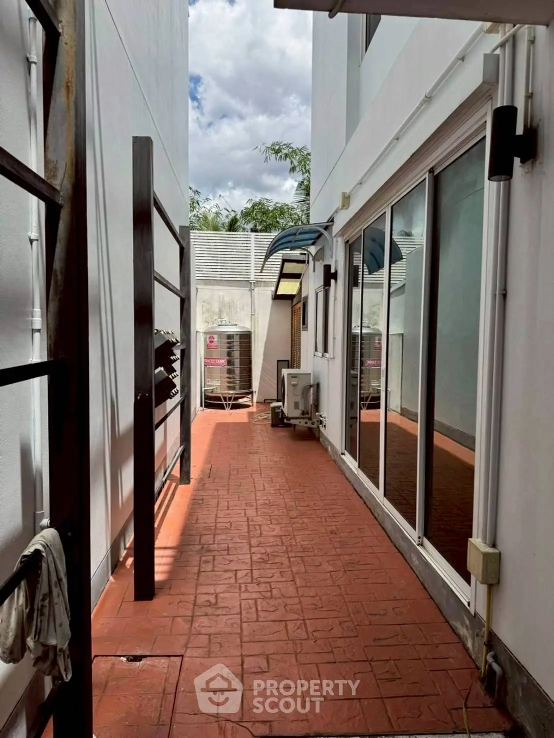 Spacious outdoor corridor with brick flooring and modern glass doors, perfect for relaxation.