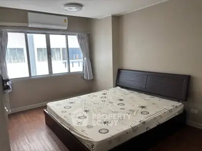 Spacious bedroom with large window and modern air conditioning unit, perfect for comfortable living.