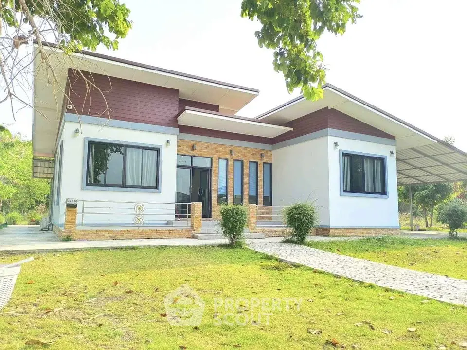 Modern single-story house with large windows and lush green lawn