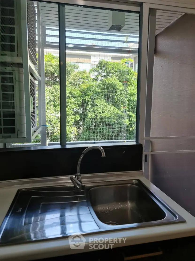 Modern kitchen sink with a lush green view through large windows, perfect for nature lovers.