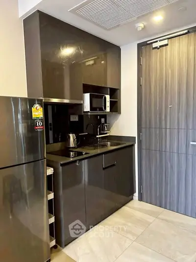 Modern compact kitchen with sleek cabinetry and stainless steel appliances in a stylish apartment.
