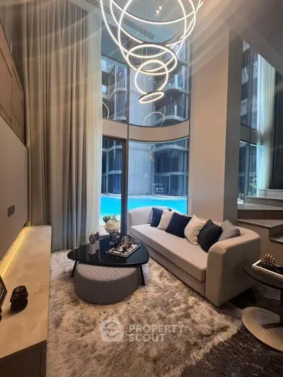 Luxurious living room with modern chandelier and pool view, featuring elegant decor and high ceilings.