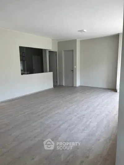 Spacious empty living room with modern flooring and neutral walls, ready for customization.
