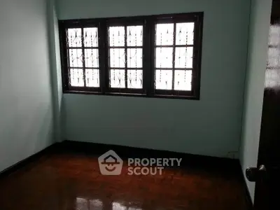 Spacious empty room with parquet flooring and large windows