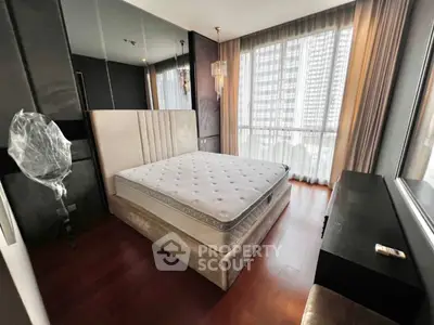 Modern bedroom with large window and elegant decor in high-rise apartment.